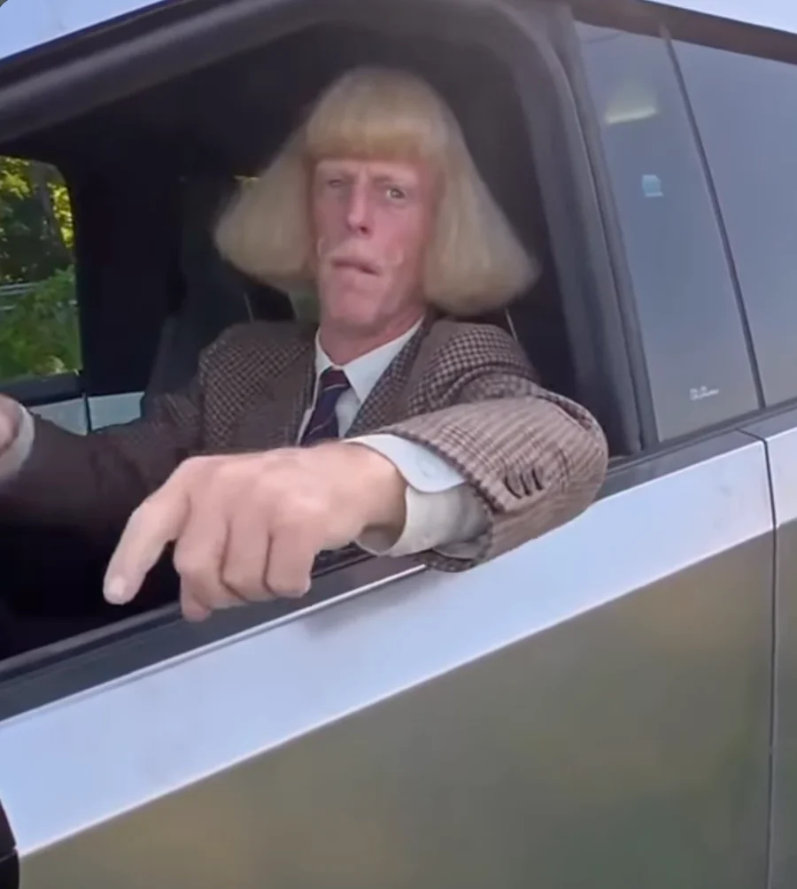 A frame from an AI remix of the fish meme: a man with a blond bowl cut points out of a car window